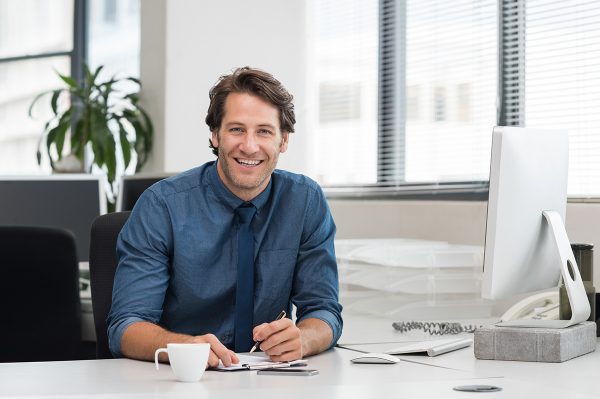 Factoring-3 Junger Arbeitgeber sitzt am Schreibtisch seines modernen Büros.